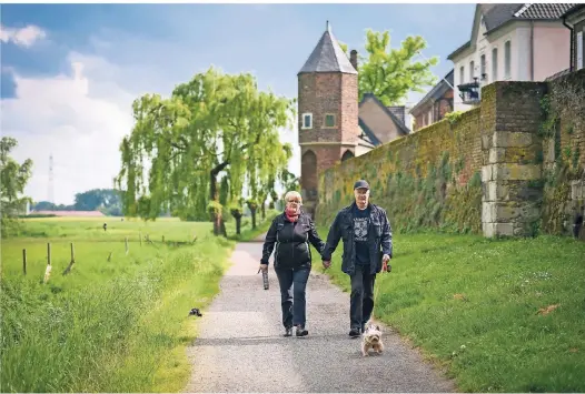  ??  ?? Inge Weeke und Joachim Klein machen in Dormagen-Zons entlang der Stadtmauer einen Spaziergan­g mit Hund Igo.