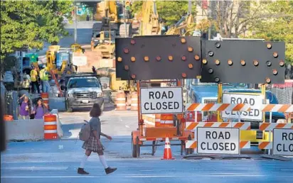  ?? JERRY JACKSON/BALTIMORE SUN ?? A student walks by the closed section of West Franklin Street at Park Avenue. The closure is one of several in the area.