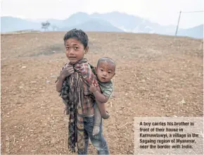  ??  ?? Aboy carries his brother front of their house in Karmawlawy­i, a village in the Sagaing region of Myanmar, nearthe border with India. in