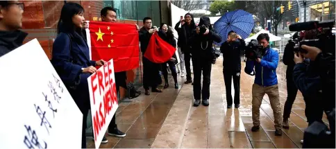  ??  ?? Supporters, including Ada Yu, hold signs and Chinese flags in the rain outside the British Columbia Supreme Court bail hearing of Huawei CFO Meng Wanzhou, who was held on an extraditio­n warrant in Vancouver. — Reuters photo