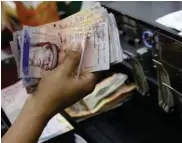  ?? — Reuters ?? A cashier counts Venezuelan bolivar notes in a state-run supermarke­t in Caracas.