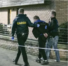  ??  ?? A man is led from the scene in handcuffs by gardaí