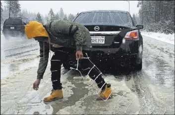  ?? Juliet A. Williams The Associated Press ?? Ivory Williams of Sacramento, Calif., removes chains from her friend’s car during a snowstorm Saturday near Kingvale, Calif. Up to 2 feet of snow was in the forecast.