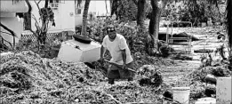  ?? GASTON DE CARDENAS/GETTY-AFP ?? Iliat Martin shovels seagrass by his home after Hurricane Irma last month in Tavenier Key, Fla. Payrolls contracted in September as hurricanes idled workers in the south.