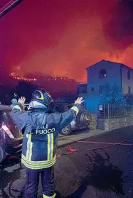  ??  ?? Un vigile del fuoco a Calci davanti al fronte del fuoco (foto Massimo Sestini). Sopra un’anziana e la badante tra gli sfollati