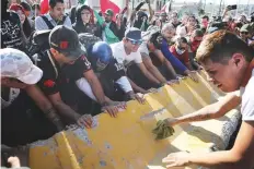  ?? AP ?? Anti-migrant protesters turn over a barrier wall protecting a migrant shelter during a demonstrat­ion in Tijuana, Mexico.