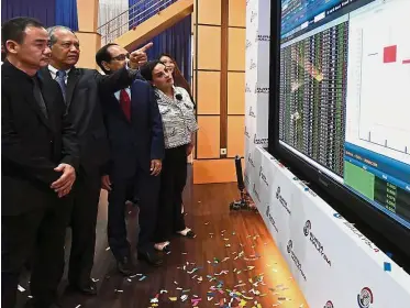  ??  ?? Impressive performanc­e: (from left) Binasat managing director Na Boon Aik and chairman Tan Sri Ahmad Fuad Ismail looking at the performanc­e of the company’s shares after the listing. — Bernama