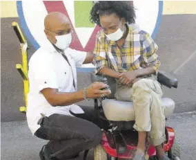  ??  ?? Garfield Virgin shows quadripleg­ic Shushanna Thomas how to operate the new motorised wheelchair he presented to her on Thursday. Thomas, who has been confined to a wheelchair for the past 11 years, was grateful for the gift, saying that it made her Christmas the best in over a decade.