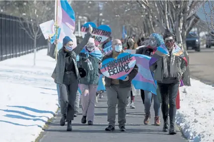  ?? By David Crary The Associated Press Toby Brusseau, Associated Press file ?? Louise Snodgrass, of Brookings, S.D., waves to passersby as she leads the protest march against a bill restrictin­g transgende­r girls from sports teams in Pierre, S.D., in March.