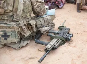  ?? ?? A soldier with his weapon beside him, talks to Malian villagers near Menaka.