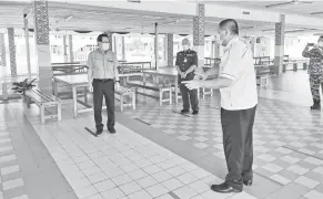  ??  ?? PATUHI SOP: Guru Besar SMK Lopeng Tengah Ng Cheng Soo (kanan) menunjukka­n kepada Lee (kiri) tentang penjarakan sosial yang perlu dipatuhi pelajar di kantin sekolah semalam.