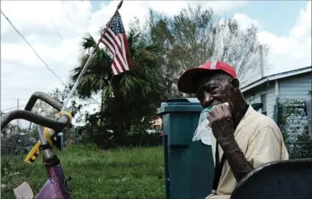  ?? SPENCER PLATT, GETTY IMAGES ?? Lee Rigley eats a sandwhich in his yard in a rural migrant-worker town waiting for emergency donations following Hurricane Irma on Thursday in Immokalee, Florida. A group of volunteers from Atlanta gave out groceries and sanitary items to hundreds of...