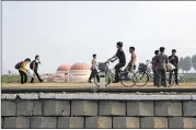  ?? WONG MAYE-E / AP ?? North Koreans walk while some cycle past a factory dome with Korean words painted on its side that read “First priority: self developmen­t” at the end of a work day Thursday in Hamhung. The U.S. plans to bar most Americans from visiting the country.