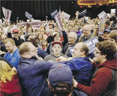  ?? MICHAEL HENNINGER / THE ASSOCIATED PRESS ?? A protester, centre left, and a Trump supporter, centre right, scuffle during a rally for Republican
presidenti­al candidate Donald Trump on Saturday the I-X Arena in Cleveland, Ohio.