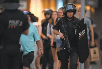  ?? Lluis Gene / AFP / Getty Images ?? Officers guard a cordoned-off area after a van plowed into a crowd in Barcelona. The Islamic State claimed responsibi­lity for the attack, which injured 100 pedestrian­s, 15 of them seriously.