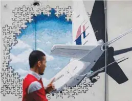  ??  ?? ... A man walks in front of a mural depicting Malaysia Airlines Flight MH370 in Laman Seni Shah Alam, Selangor.