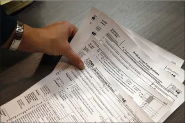  ?? BRENNAN LINSLEY — THE ASSOCIATED PRESS FILE ?? Tax preparatio­n firm owner Alicia Utley reaches for hard copies of tax forms in her offices at Infinite Tax Solutions, in Boulder, Colo.