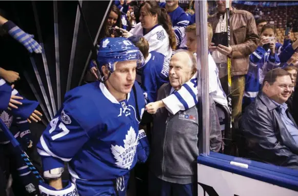  ?? MICHELLE SIU/THE NEW YORK TIMES ?? Vic Braknis, 77, an usher who has been with the Maple Leafs for 25 years, opens the gate for Leo Komarov. Braknis is among the longest-tenured staff members in the NHL.