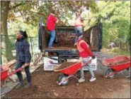  ?? EVAN BRANDT — DIGITAL FIRST MEDIA ?? Moasic Community Garden manager Laura Washington and Michael Eze, 15, were part of the train of Hill School students moving mulch donated by John Jermacans Style of Skippack and shoveled by John and Christian DeVol, 17.