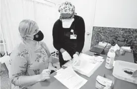  ?? MARY ALTAFFER/AP ?? A nurse goes over paperwork with mosque member Zejreme Rodoncic after giving her the COVID-19 vaccine Thursday in the Staten Island borough of New York.
