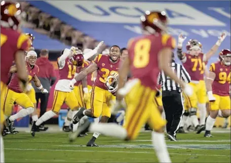 ?? Ashley Landis Associated Press ?? USC PLAYERS RUN onto the f ield at the Rose Bowl on Saturday after overcoming an 18- point second- half deficit to defeat UCLA.