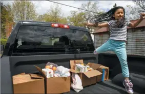  ?? JACQUELYN MARTIN - ASSOCIATED PRESS ?? Allison, 5, leaps over four boxes of food that her parents have painstakin­gly gathered from food banks and churches, over the course of two weeks, to bring to her aunts and cousins in Baltimore who are having trouble finding enough food to eat, April 14 in Washington. One week prior her cousins, 14, 11, and 5 years old, were down to one meal a day.