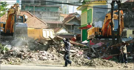  ??  ?? RATA TANAH: Petugas Dinas PU Bina Marga dan Pematusan Surabaya membongkar persil bangunan untuk pelebaran jalan di Simpang Dukuh kemarin.