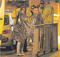  ?? REUTERS ?? Two women wrapped in thermal blankets stand near the Manchester Arena, where US singer Ariana Grande had been performing in Manchester on Tuesday.