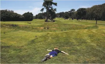  ?? Lea Suzuki / The Chronicle ?? Luca, 11, of San Francisco lies in the grass at the Presidio Golf Course while enjoying some time outdoors with his mother and brother. Golfers began reclaiming the links on Monday.