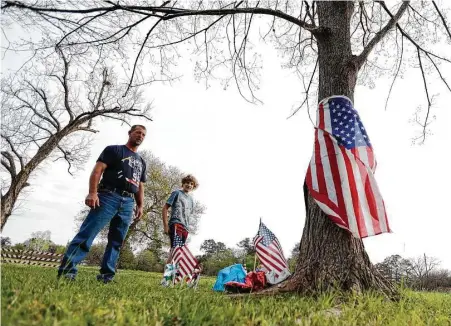  ?? Karen Warren / Houston Chronicle ?? Dale Jozwiak and his son Corbin, 11, look on Wednesday at a memorial next to a tree, where Jozwiak found the bald eagle that was shot last week. The eagle and its mate had been fixtures in the Houston neighborho­od along White Oak Bayou for several years.