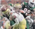  ??  ?? FSU quarterbac­k Deondre Francois is hit hard by Miami’s Jonathan Garvin during the second half of Saturday’s game.