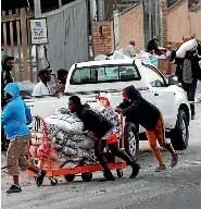  ?? AP ?? A trolley of rice stolen from a factory is pushed along a road in Mobeni, south of Durban, in KwaZulu-Natal. The photograph was taken on July 15.