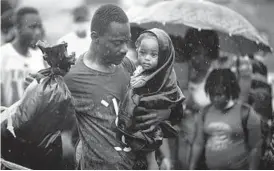  ?? IVAN VALENCIA/AP ?? A Haitian migrant carries a baby to a boat Tuesday that will take them to Capurgana, on the border with Panama, from the coastal city of Necocli, Colombia.