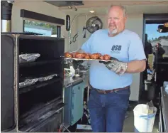  ??  ?? Scott Smith, president of the Georgia Barbecue Championsh­ip, pulls chicken legs out of the smoker to hand off to judges during a private event at the fairground­s over the weekend.