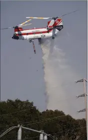  ?? JANE TYSKA — STAFF PHOTOGRAPH­ER ?? A helicopter drops water on a wildfire in the Emerald Hills near PG&E's Edgewood substation in Redwood City on Tuesday.