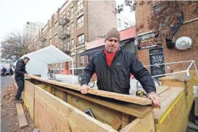  ?? KATHY WILLENS/AP ?? Wade Hagenbart, right, lifts the top off a wooden support barrier for a tent he’s constructi­ng for outdoor dining at Guero’s, the tiny but popular taco and margarita restaurant he co-owns in the Prospect Heights neighborho­od of Brooklyn on Dec. 2 in New York.