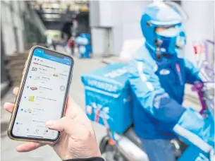  ??  ?? A customer uses a mobile phone to place a food delivery order in Hangzhou. Developers whose apps have become essential to daily life in China are adding innovative medical applicatio­ns to help in the fight against Covid-19.