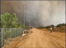  ?? PHOTO COURTESY CONNIE MAVROLAS ?? LIttlerock resident Jeff Gardener looks at flames from the Bobcat Fire while standing on 121st Street East.