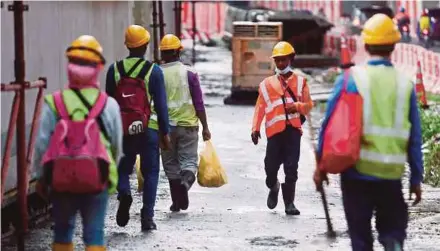  ?? FILE PIC ?? Constructi­on workers leaving their worksite after finishing their shift in Kuala Lumpur.