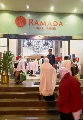  ??  ?? Plans not taking off: Pilgrims entering Ramada hotel after not being able to take a flight home to Malaysia.