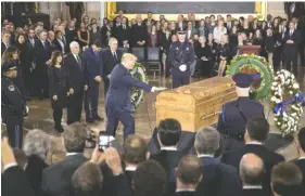  ?? THE ASSOCIATED PRESS ?? President Donald Trump touches the casket of Rev. Billy Graham, who died last week at age 99, during a ceremony Wednesday in the Capitol Rotunda.