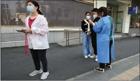  ?? (AP/Mark Schiefelbe­in) ?? A worker helps people register on their smartphone as they stand in line for covid-19 tests at a testing site during the second consecutiv­e day of mass testing in Beijing.