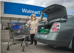  ?? ANDRES KUDACKI / THE NEW YORK TIMES ?? A woman loads her car Wednesday after shopping at a Walmart store in Secaucus, N.J. Walmart said its home delivery service for groceries would be available to 40 percent of households in the United States by the end of the year.