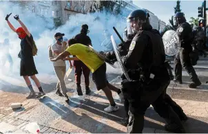  ?? — AFP ?? Shield shove: Police pushing a protester back during the demonstrat­ion near the White House earlier this week.