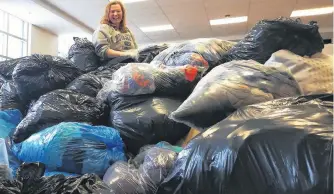  ?? ANDREW WATERMAN/THE TELEGRAM ?? A couple of weeks ago, this pile of donations wasn't here, Nicole Edwards said. But volunteeri­ng to sort through the pile, even if it is this big, makes her feel great, she says.