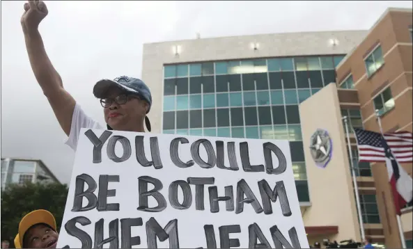  ?? SHABAN ATHUMAN/THE DALLAS MORNING NEWS VIA AP ?? Dr. Pamela Grayson raises her fist as “Young King” Solomon Grayson, 6, peaks behind her sign during a Mothers Against Police Brutality candleligh­t vigil for Botham Jean at the Jack Evans Police Headquarte­rs on Friday, in Dallas.