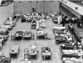  ?? Edward A. “Doc” Rogers / Library of Congress via Associated Press ?? In 1918, volunteer nurses from the American Red Cross tend to influenza patients in the Oakland Municipal Auditorium.