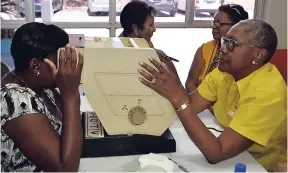  ??  ?? A member of the Lions Club of New Kingston conducts an eye-screening examinatio­n during the annual health fair organised by Food For The Poor Jamaica, in partnershi­p with the Lions Club of New Kingston. The event, which benefited over 700 persons, was...