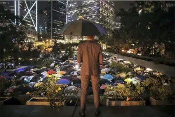  ?? ELSON LI/HK01 VIA AP ?? A man holding an umbrella looks at people with umbrellas gathered at Chater Garden to give support to the recent protests against the extraditio­n bill, at the financial district in Hong Kong, Thursday. The Chinese army has released a promotiona­l video for its Hong Kong-based troops at a time of uncertaint­y over whether the military will intervene in the city’s summer of protest.