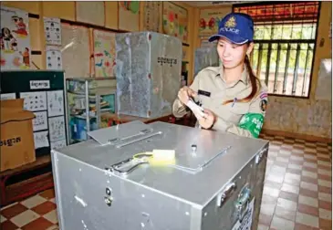  ?? HENG CHIVOAN ?? A police officer places her vote in a ballot box at a Kampong Cham school during the 2013 election.